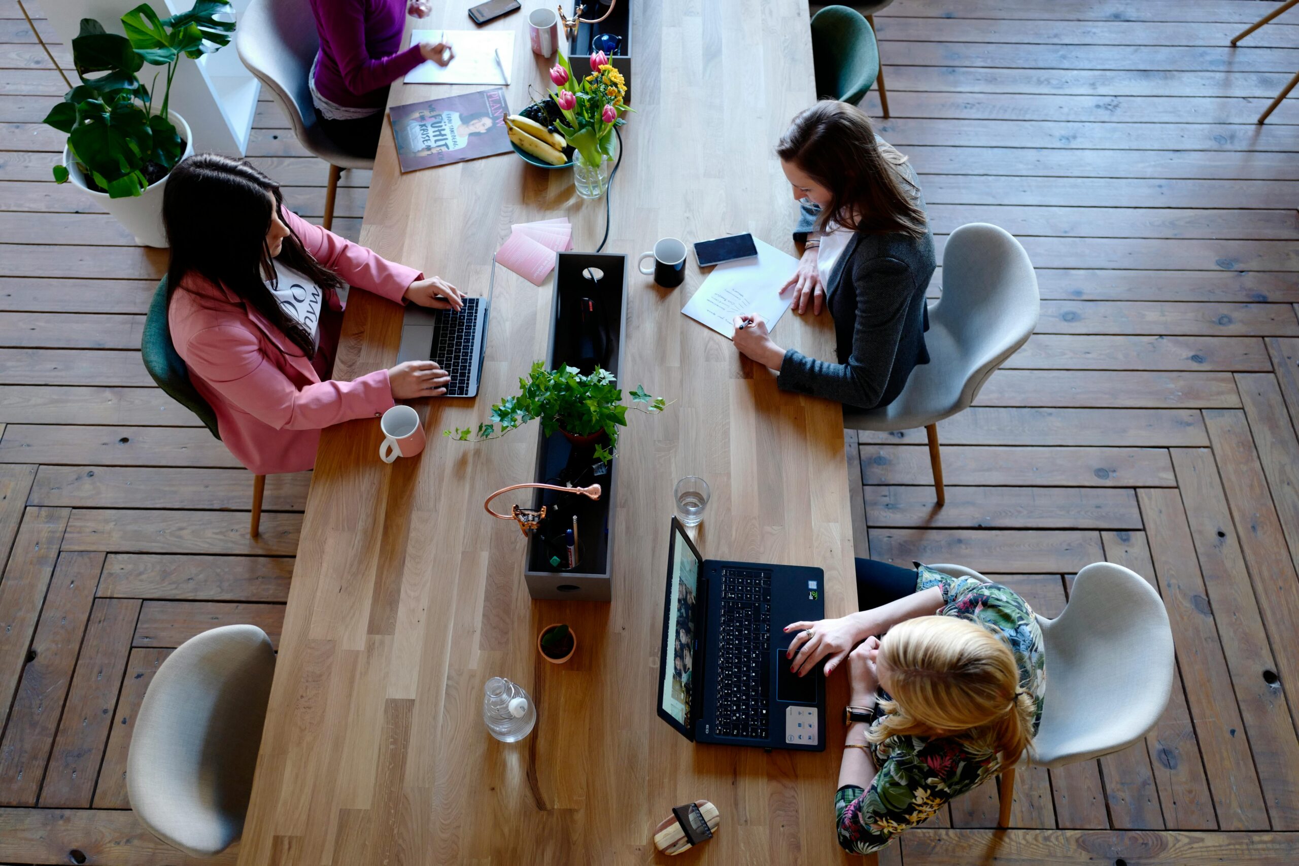 Fibra y Movil Overhead view of diverse women professionals working in a modern office setting, fostering collaboration and teamwork.