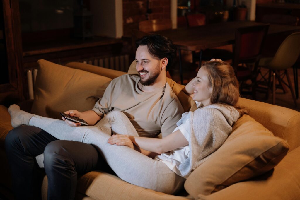 Fibra y Movil A loving couple relaxing on the sofa in a cozy home interior during the evening, enjoying a peaceful moment together.