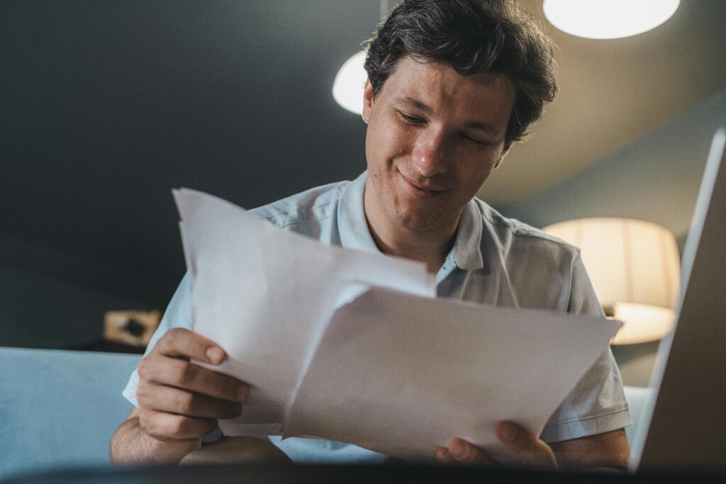 ENERGIA A cheerful man reading papers in a cozy indoor setting, radiating positivity.